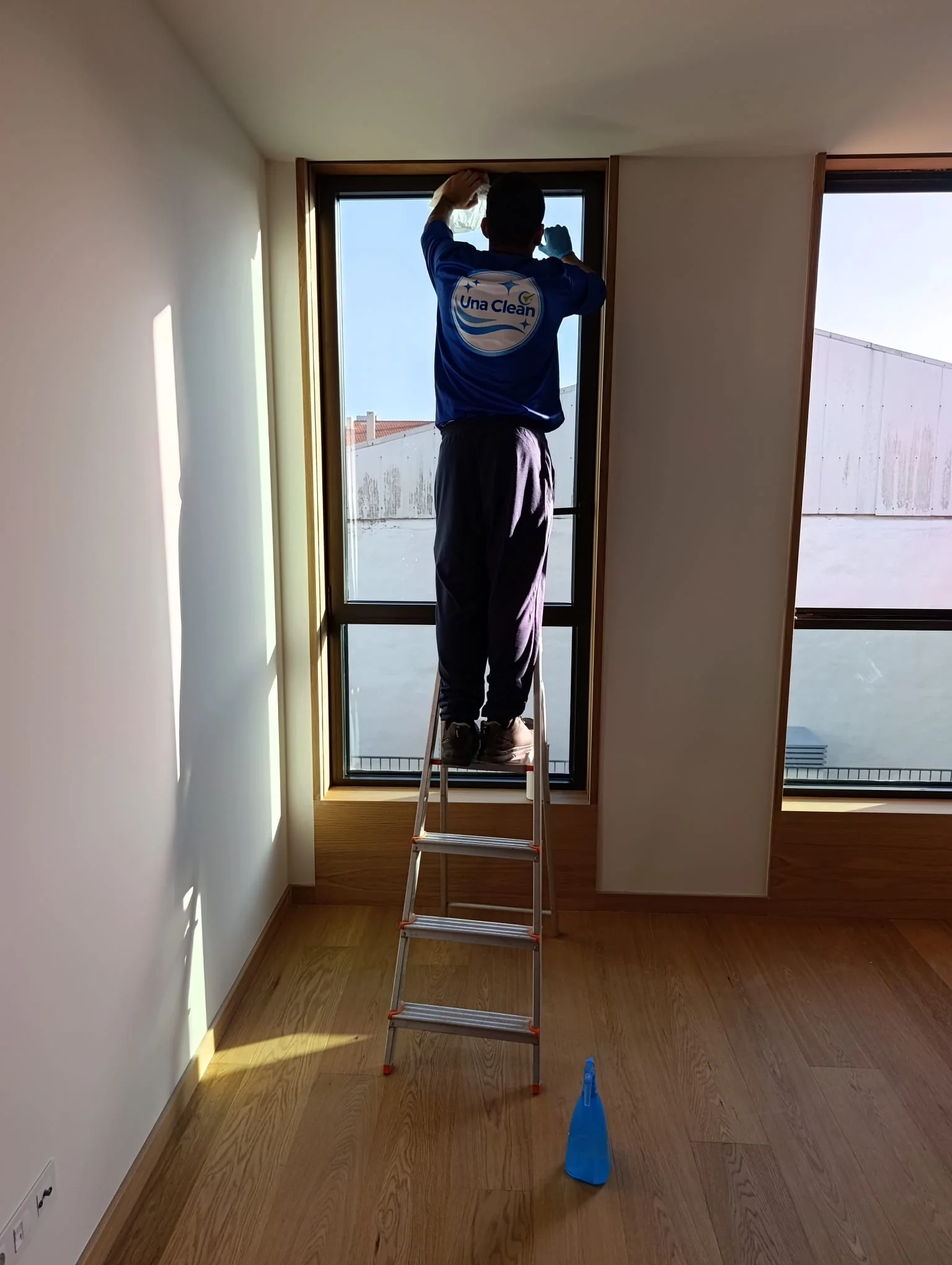 Profissional da Una Clean a limpar um vidro alto após trabalhos de obra